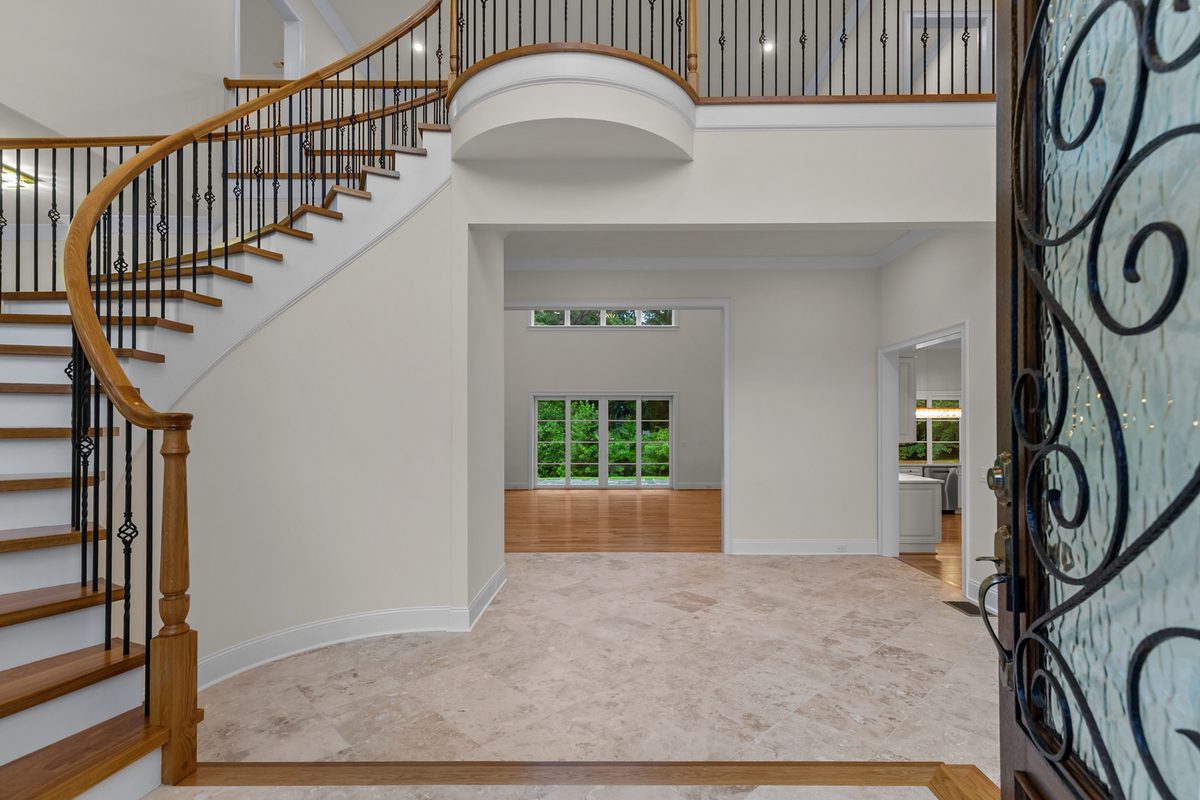 Foyer with curved staircase, travertine floor and iron entry door, Henderson Mill new custom home, DeKalb County, GA