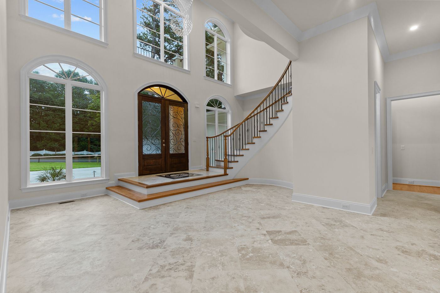 Two-story foyer with arched windows, arched wood entry door, and a curved staircase, Henderson Mill new custom home, DeKalb County, GA