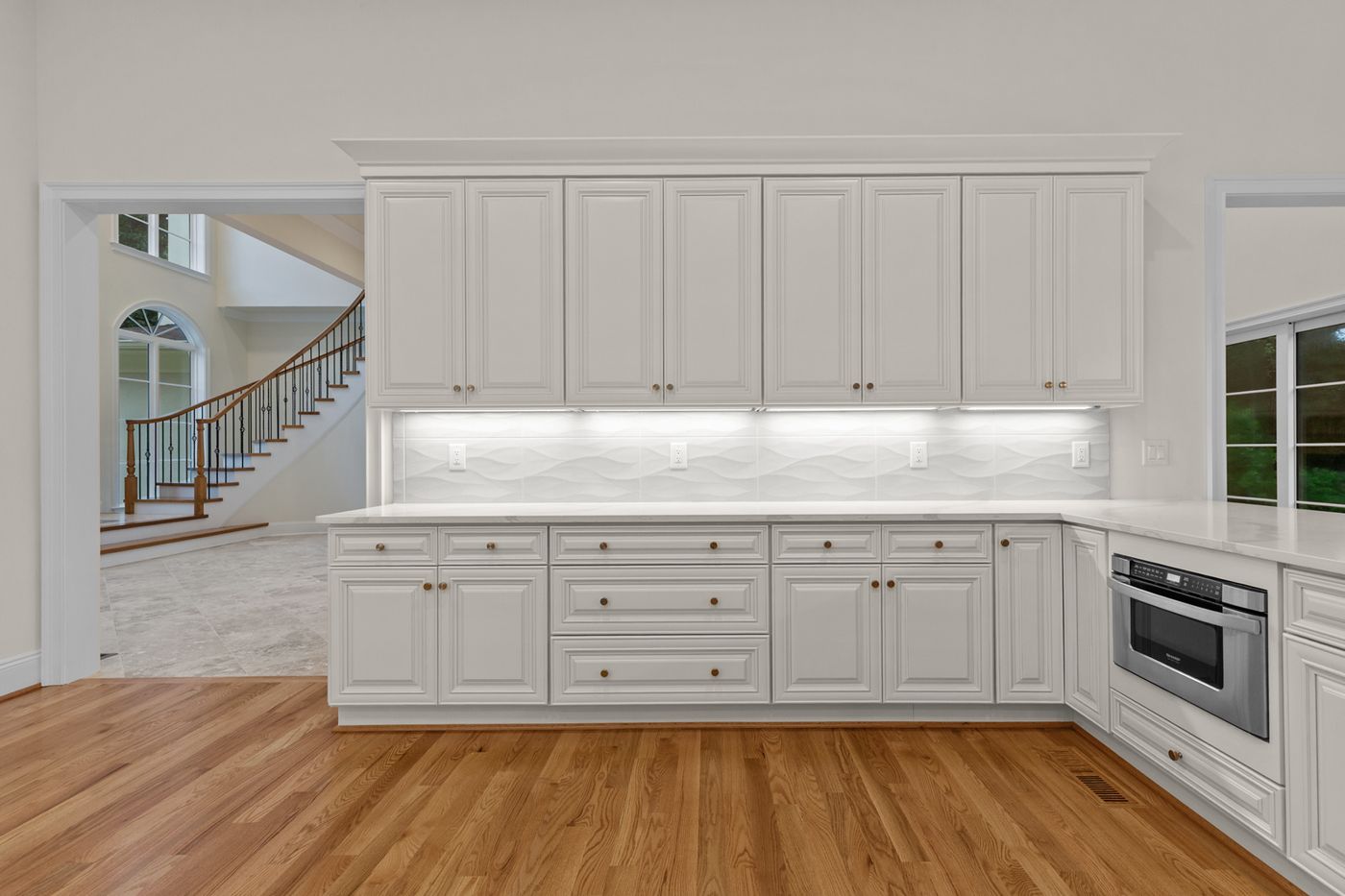 White kitchen cabinetry with a view through to the curved staircase, Henderson Mill new custom home, DeKalb County, GA