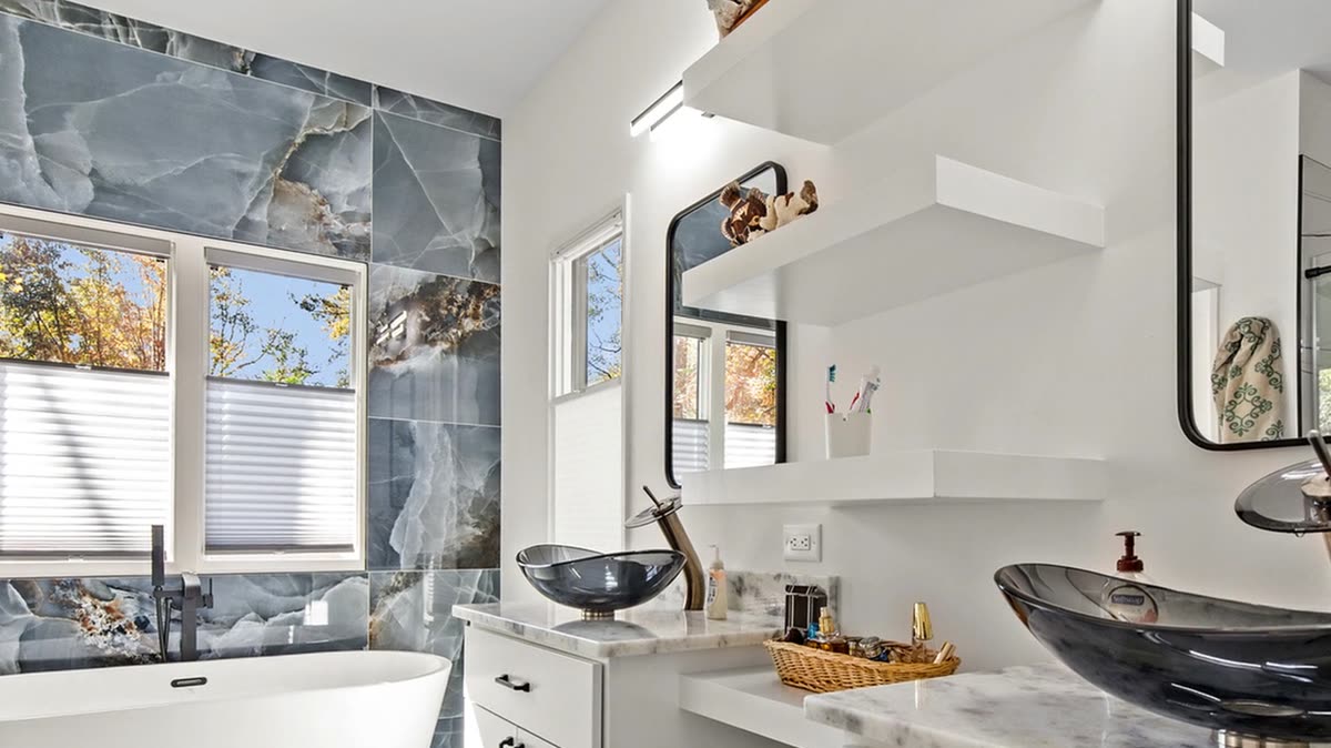 Primary bath with stone feature wall, freestanding tub, and glass vessel sinks, Old Orchard new custom home, Marietta, GA