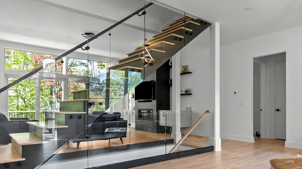 Floating wood staircase with glass rail above an open living area, Old Orchard new custom home, Marietta, GA
