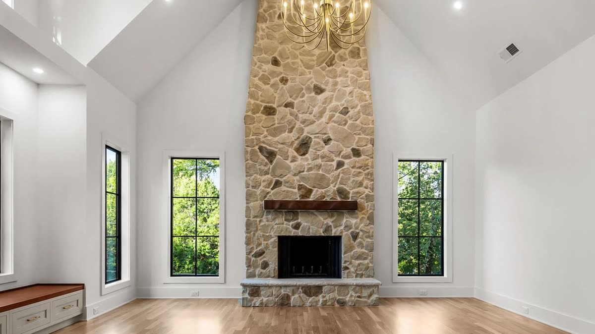 Vaulted great room with a floor-to-ceiling stone fireplace and black-framed windows, Skylane new custom home, Marietta, GA