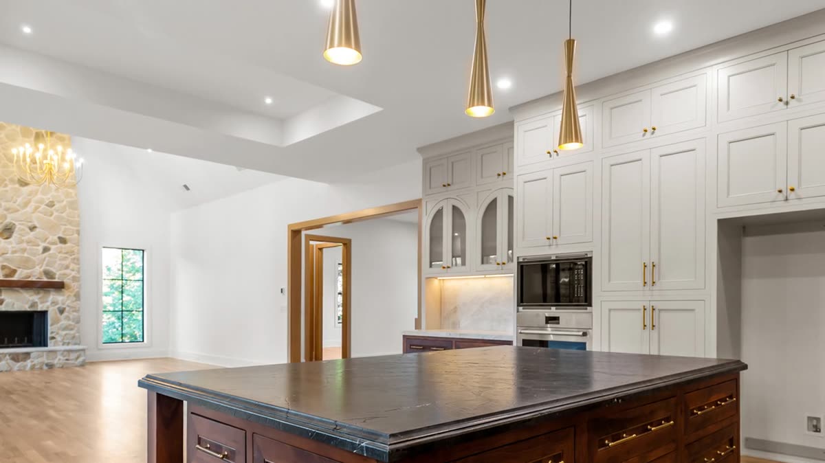 Kitchen with white custom cabinetry, brass pendants, and a stained island, Skylane new custom home, Marietta, GA