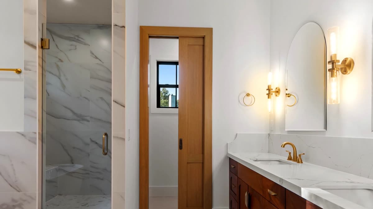Primary bath with marble shower, wood vanity, and brass fixtures, Skylane new custom home, Marietta, GA