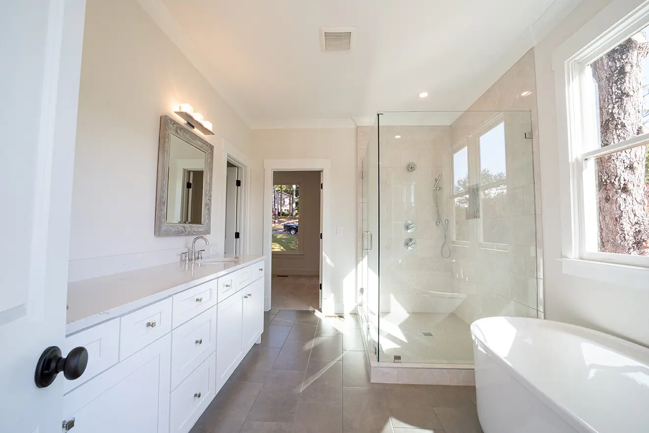 A bathroom with white cabinets and a walk in shower.