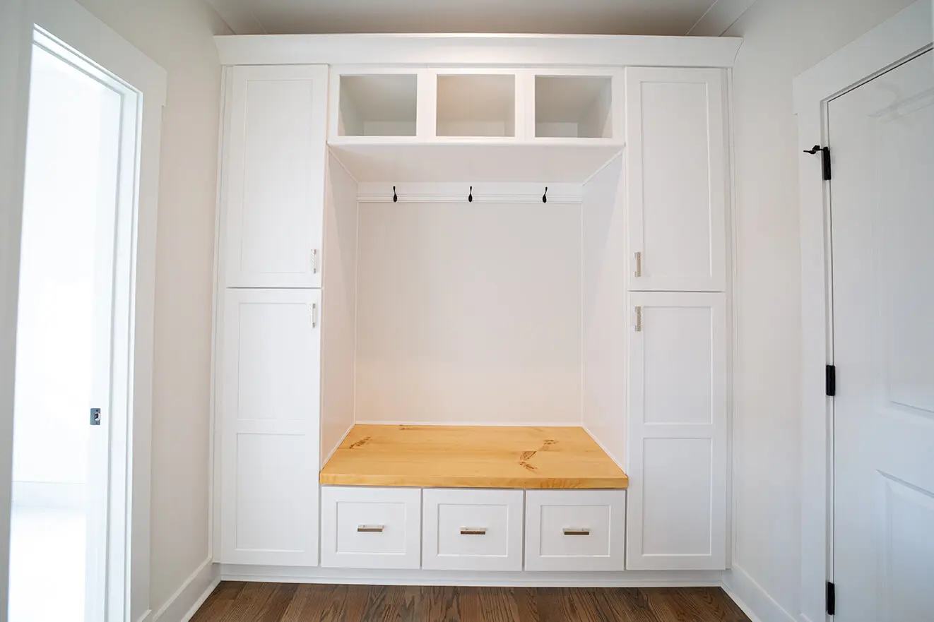 A white room with wooden floors and cabinets.