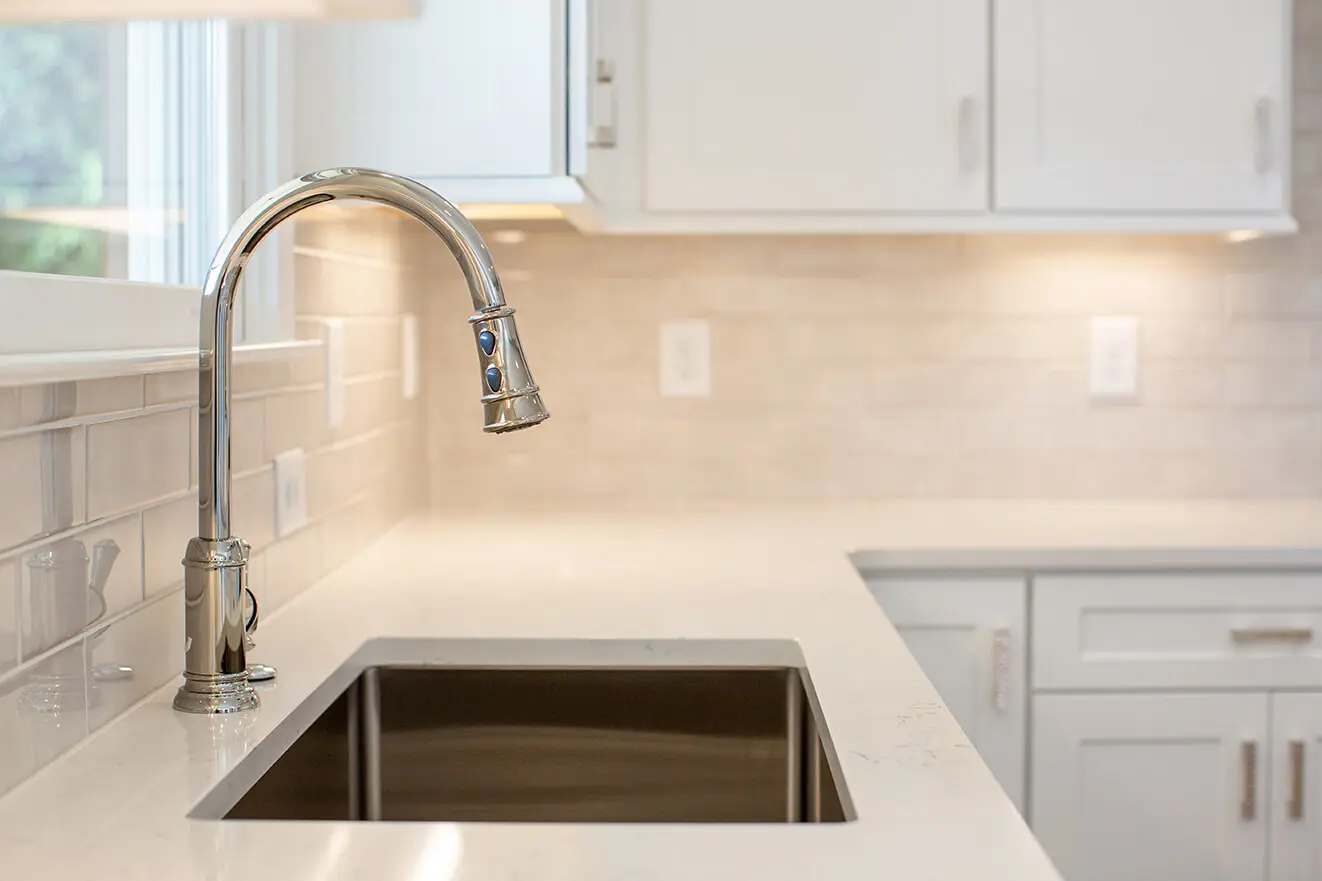 A kitchen with white counters and a sink.