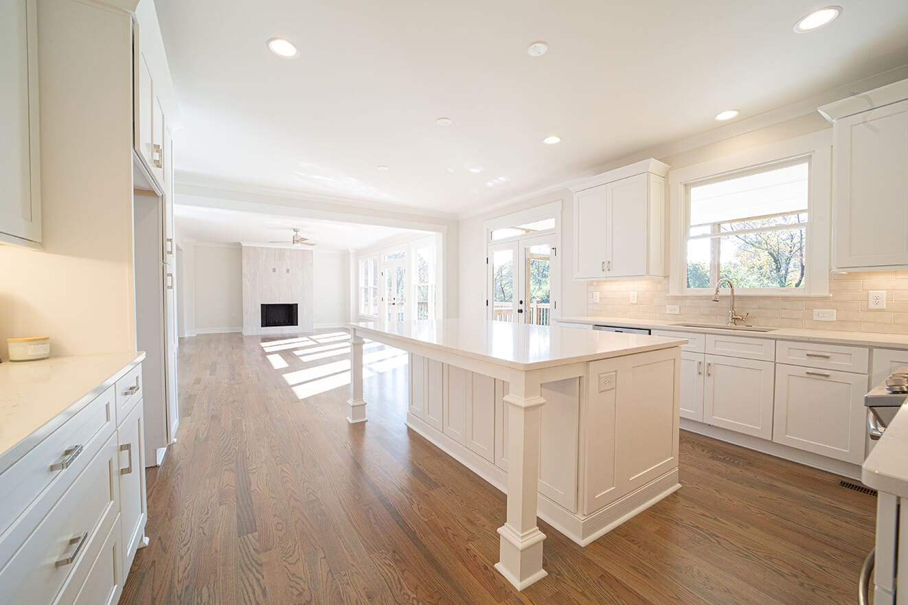 A large white kitchen with wood floors and white cabinets.