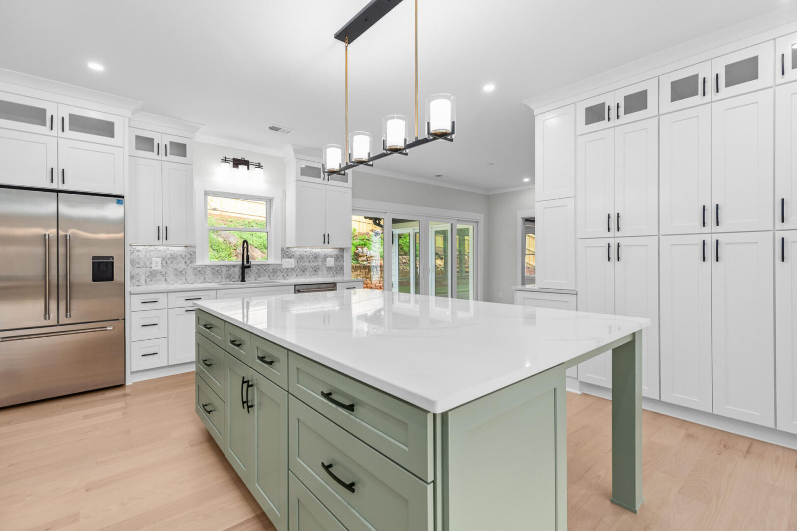 A large kitchen with white cabinets and green island.