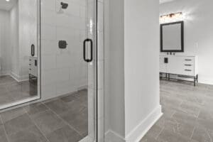 Modern bathroom featuring a glass-enclosed shower, a vanity with a large mirror, and gray tile flooring.