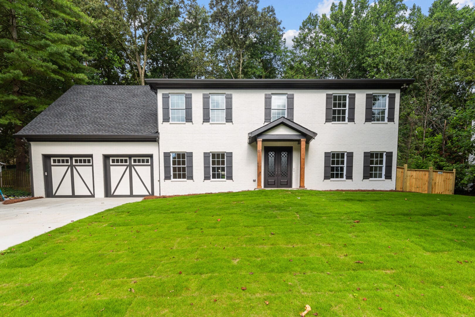 White brick house with black shutters and garage.