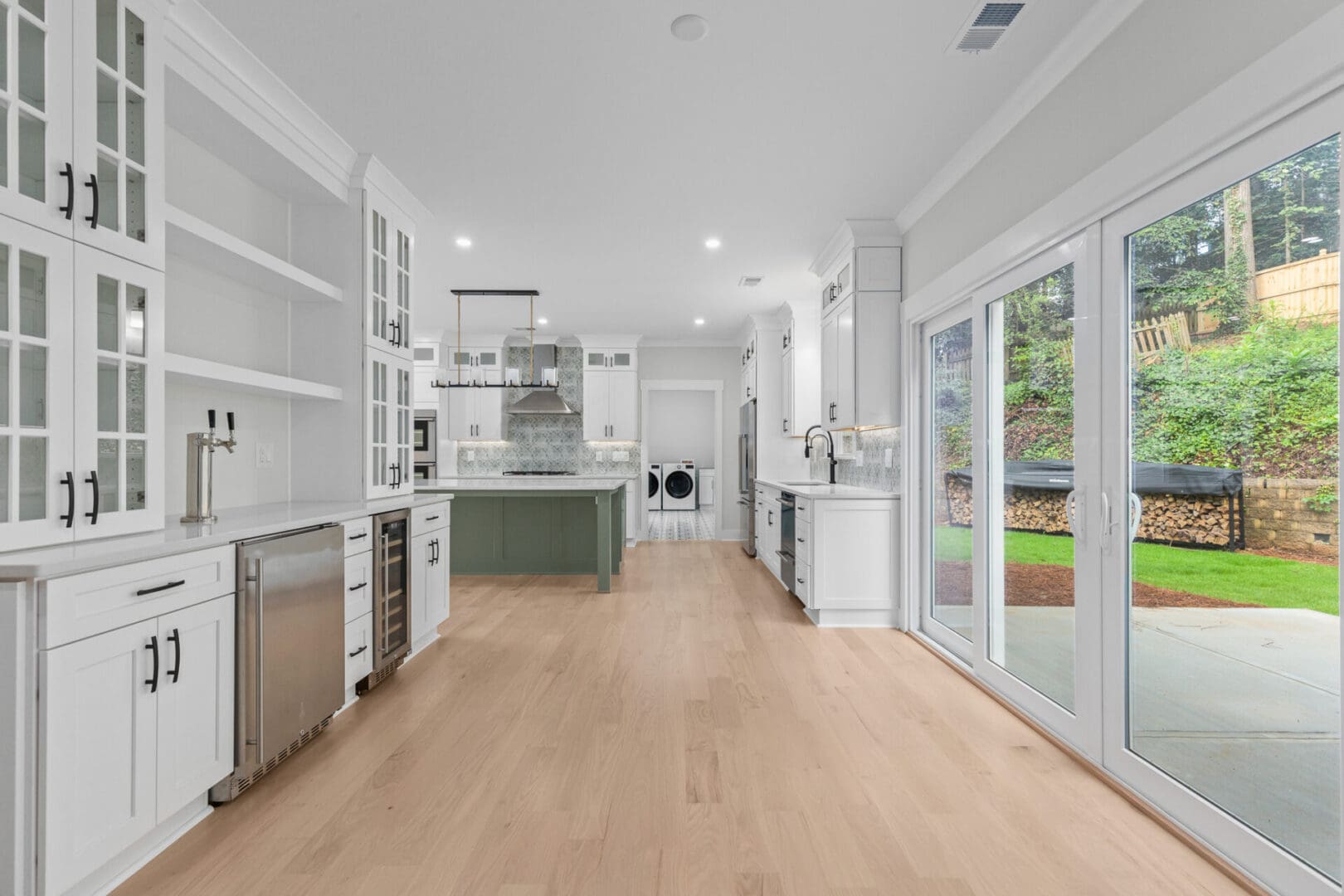 Modern kitchen with white cabinets and hardwood floors.
