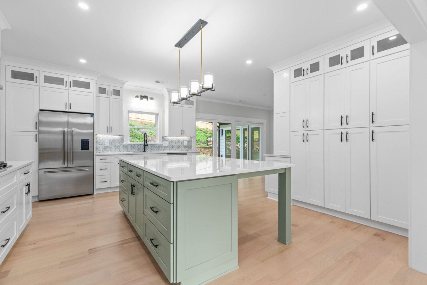 Green kitchen island with white cabinets.