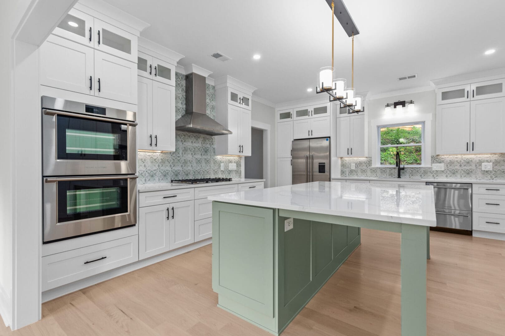Modern kitchen with green island and white cabinets.