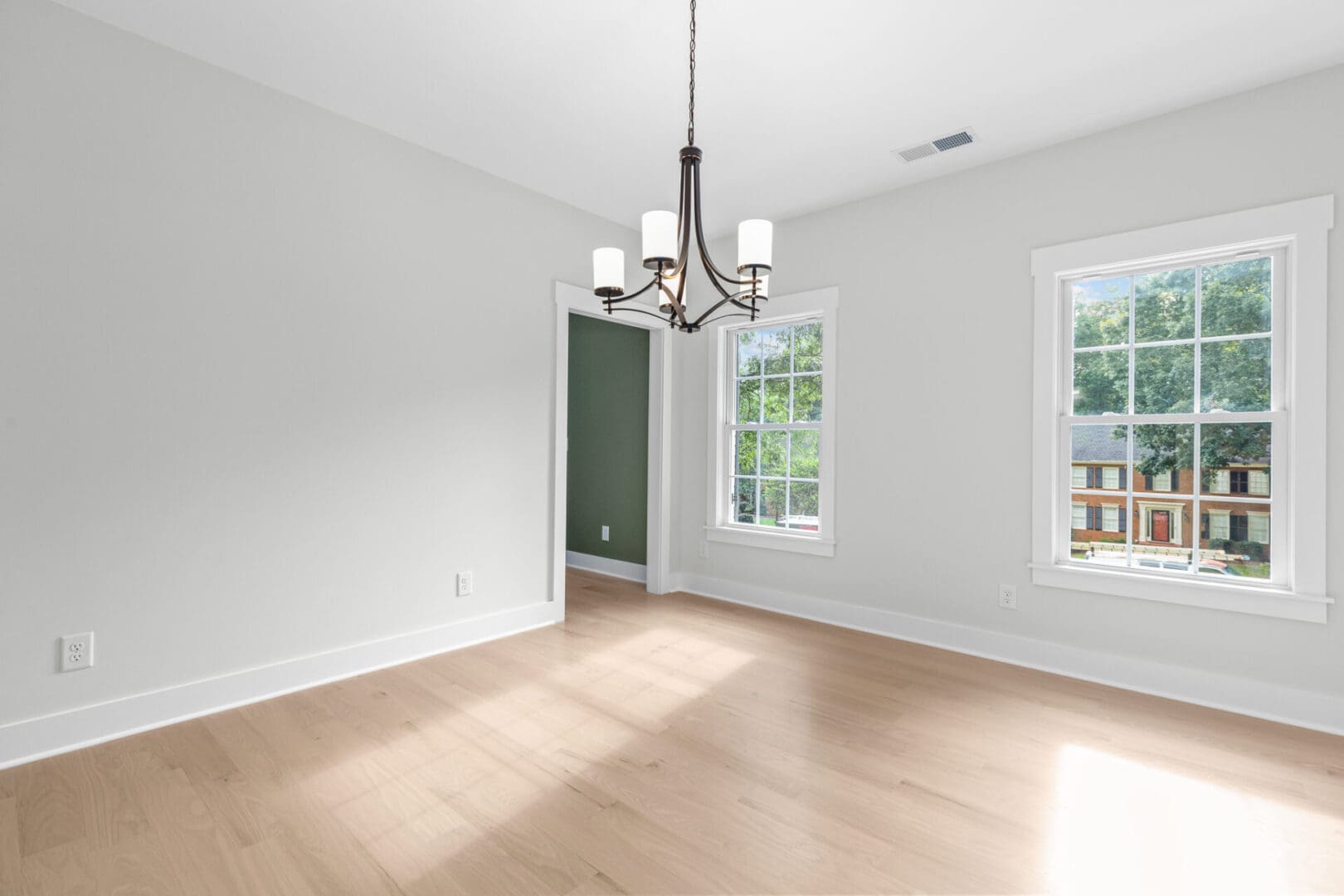 Empty room with hardwood floors and chandelier.