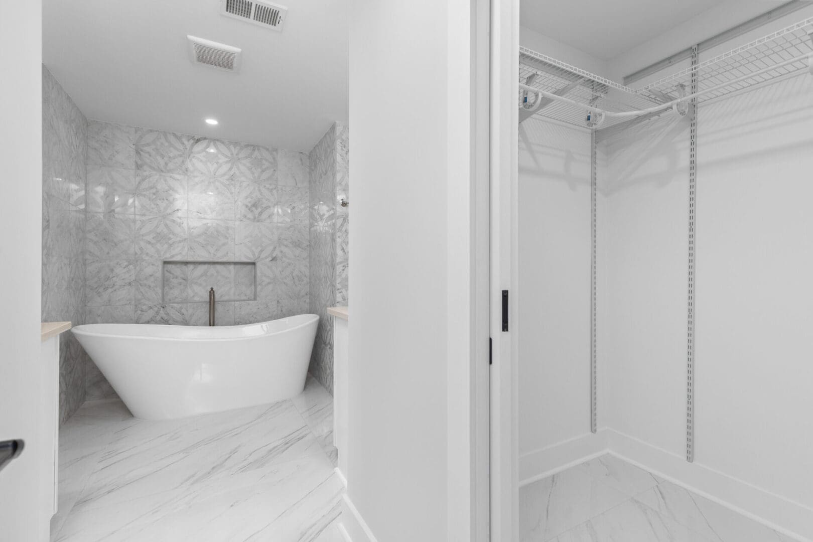 White bathroom with freestanding bathtub and closet.