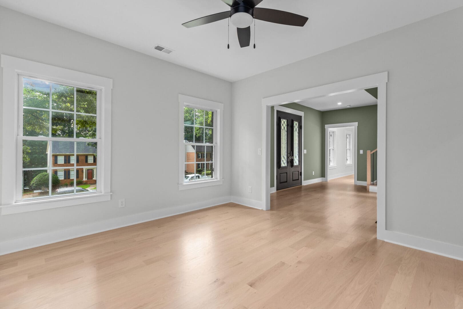 Empty room with hardwood floors and windows.