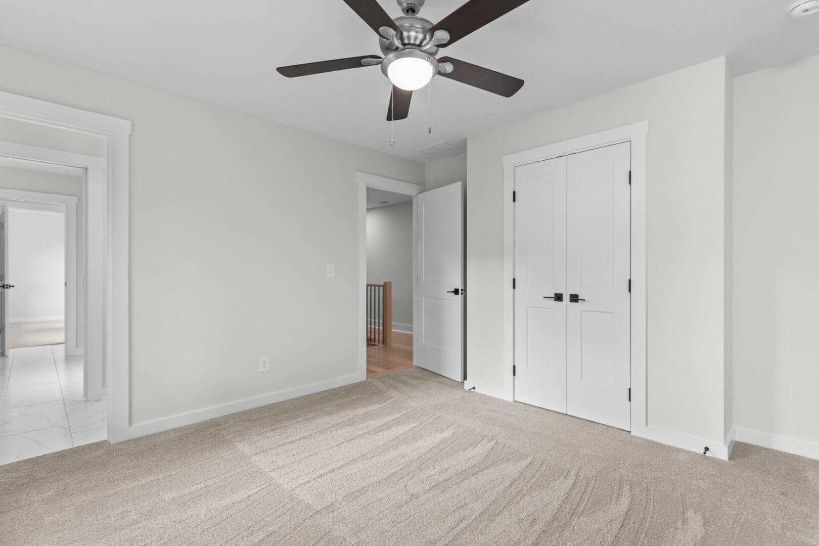 Empty bedroom with carpet and ceiling fan.