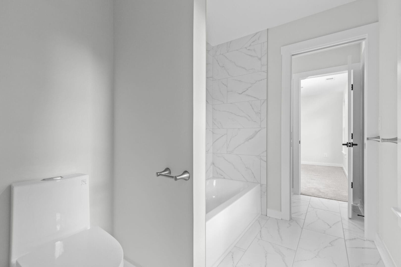 White bathroom with a toilet and tub.