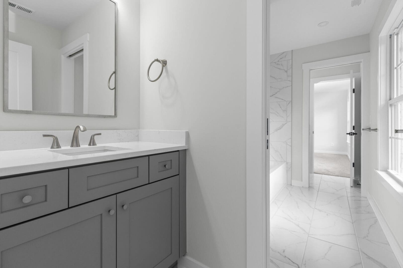 Modern bathroom with grey cabinets and marble floor.