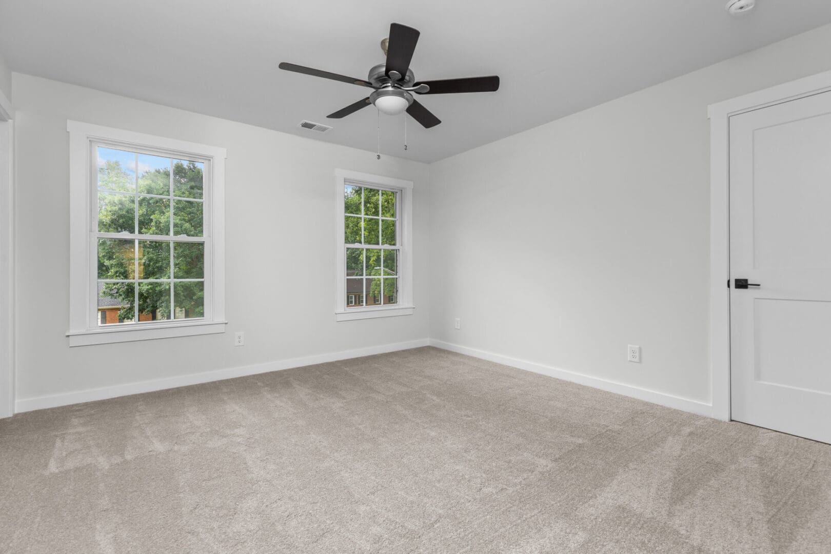Empty room with carpet, windows, and a door.