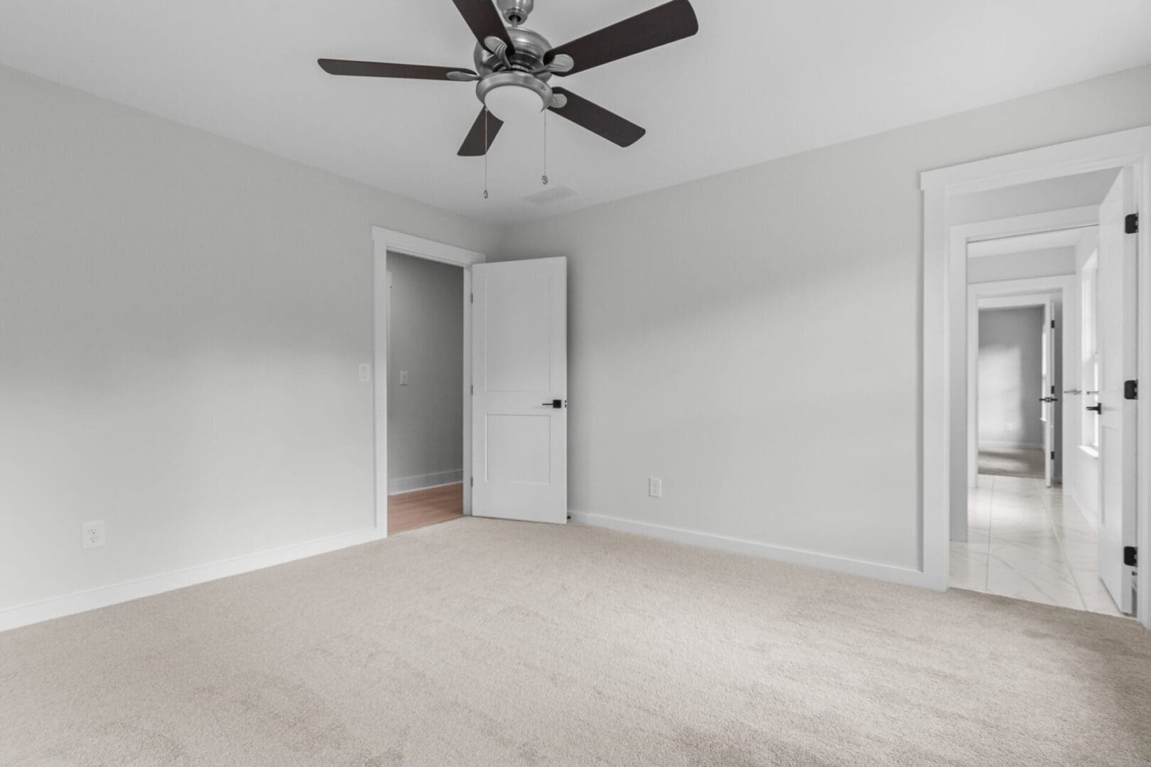 Empty bedroom with ceiling fan and doors.