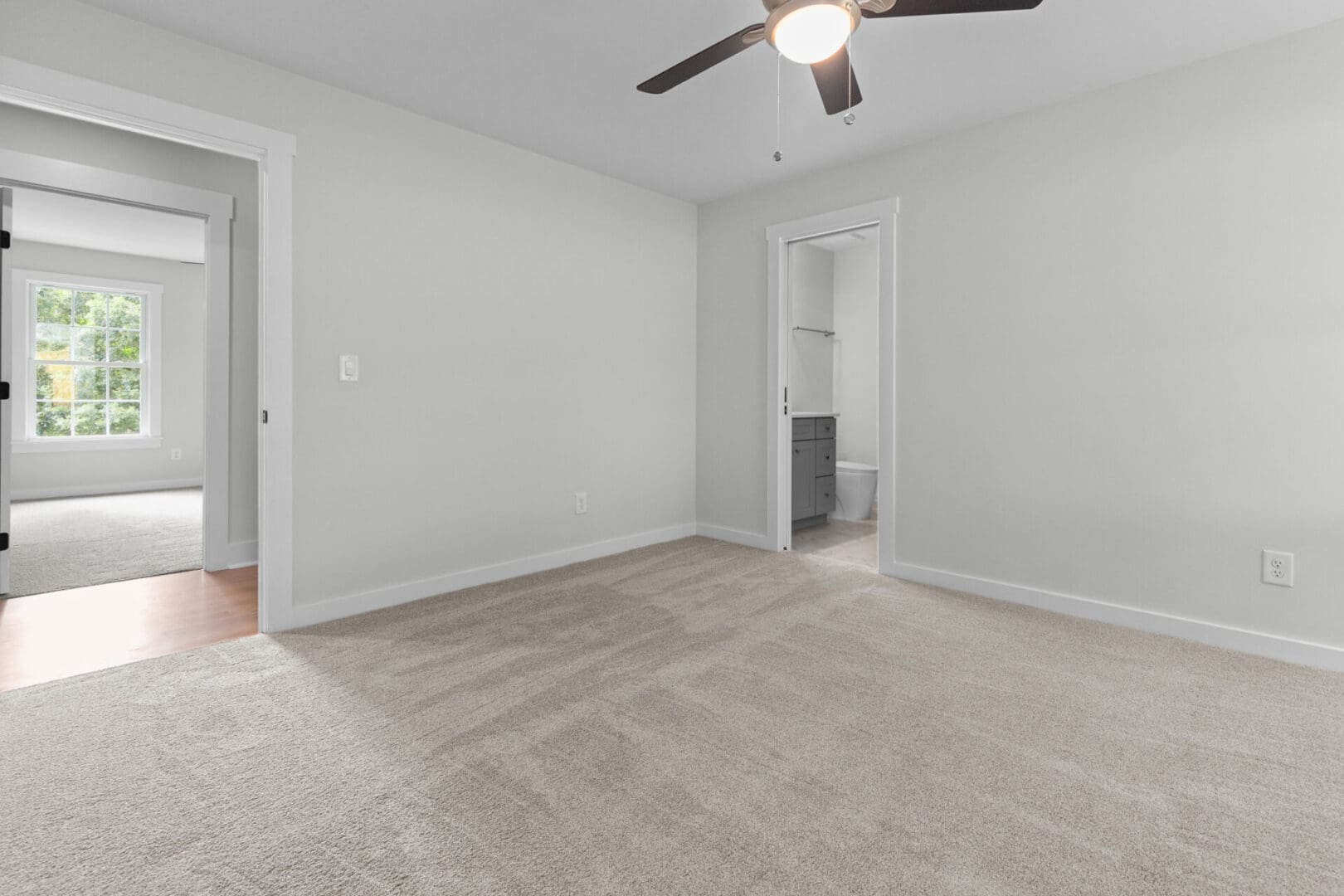 Empty bedroom with carpeted floor and bathroom door.