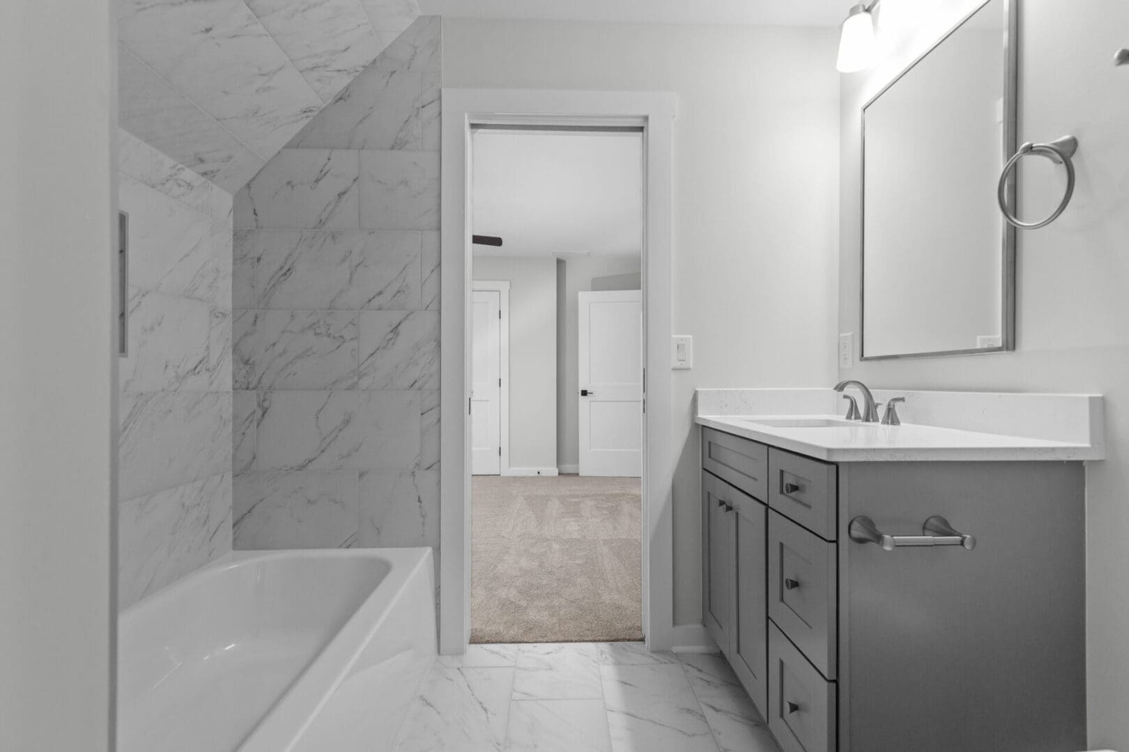 Modern bathroom with white tub and gray cabinets.