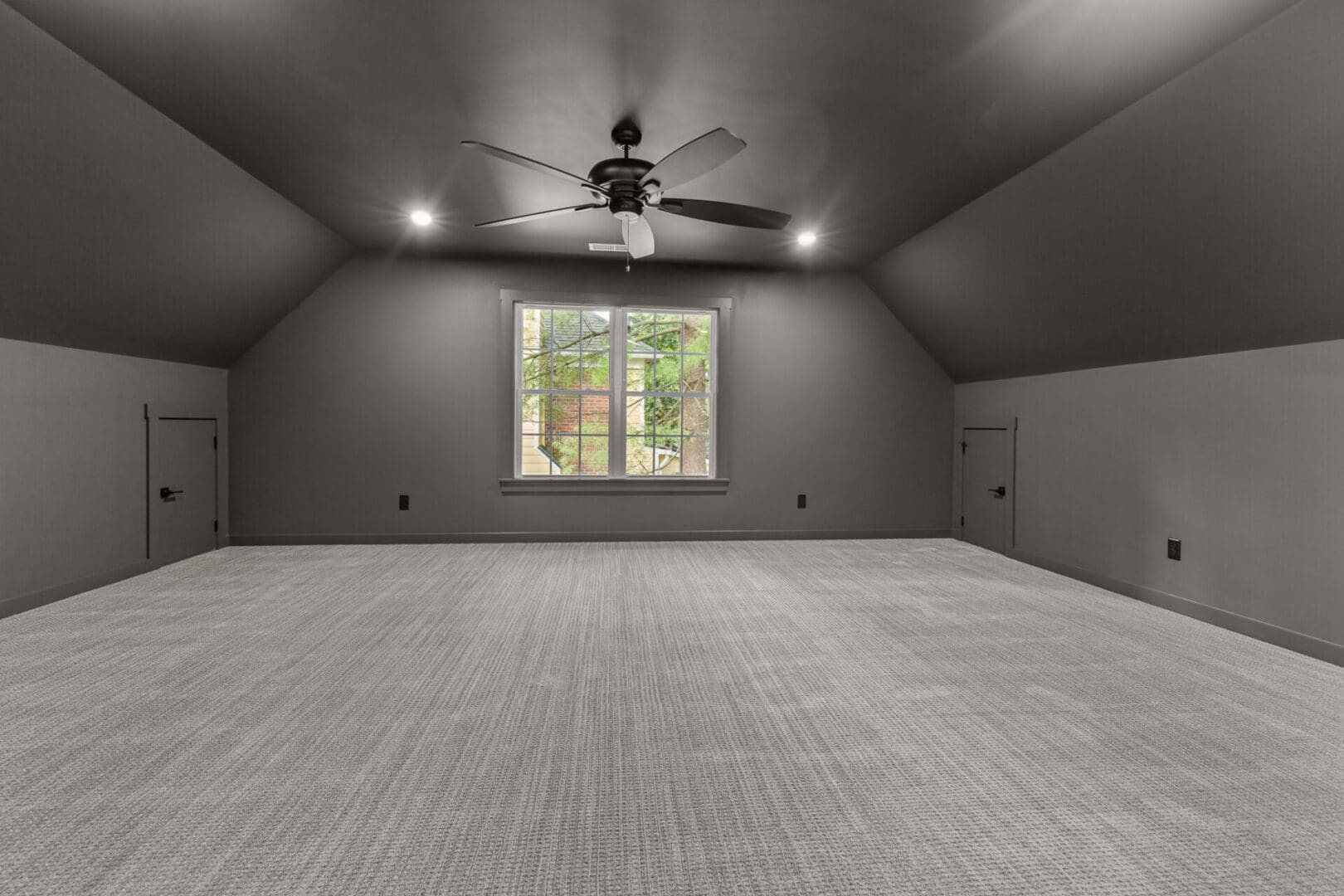Empty attic room with carpet and window.