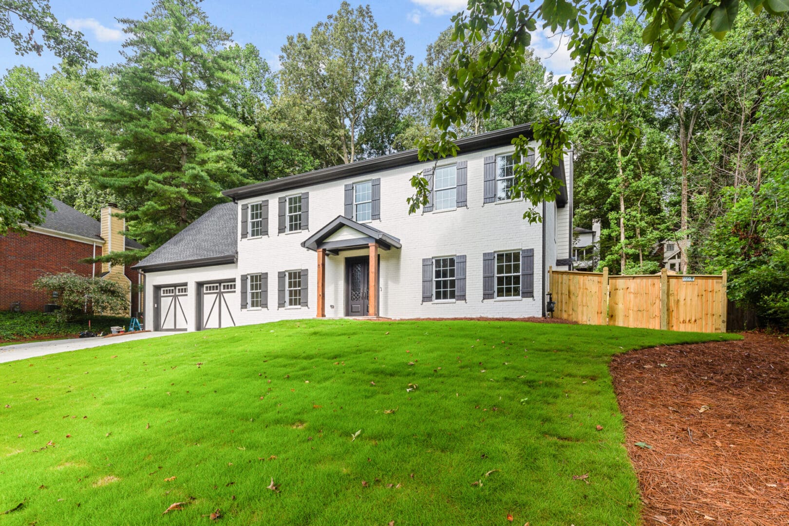 White house with black shutters and a green lawn.