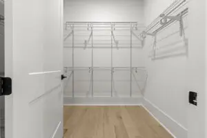 A walk-in closet with empty wire shelving on the walls and a hardwood floor. The door is partially open.