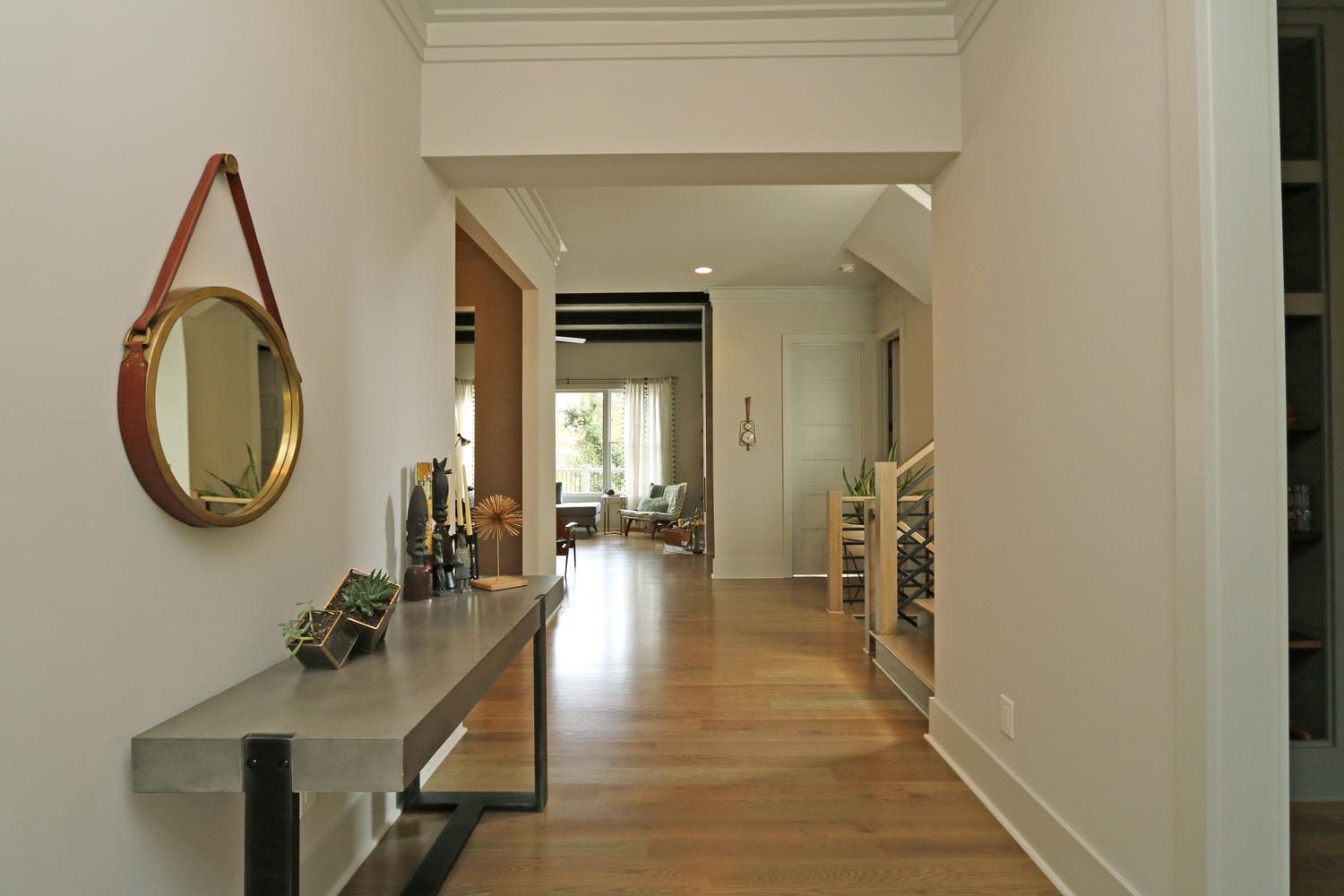 A hallway with a round mirror and table.