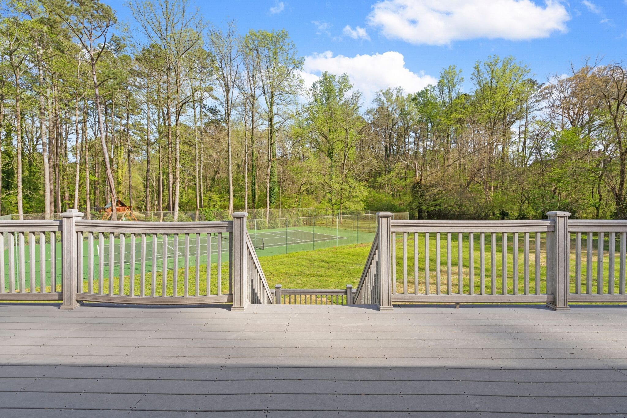 Deck overlooking tennis court in woods.