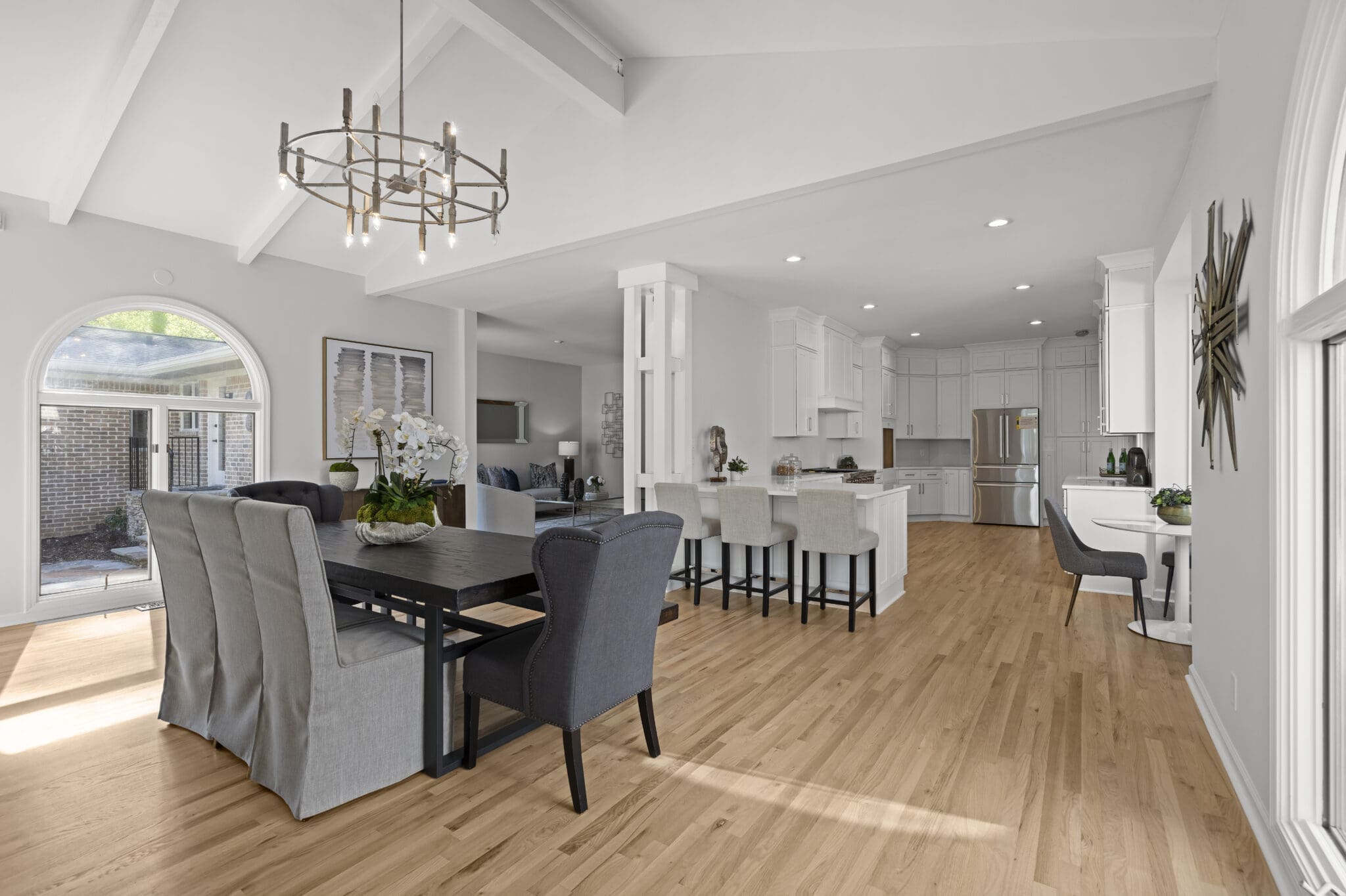 Modern dining room with white kitchen in background.