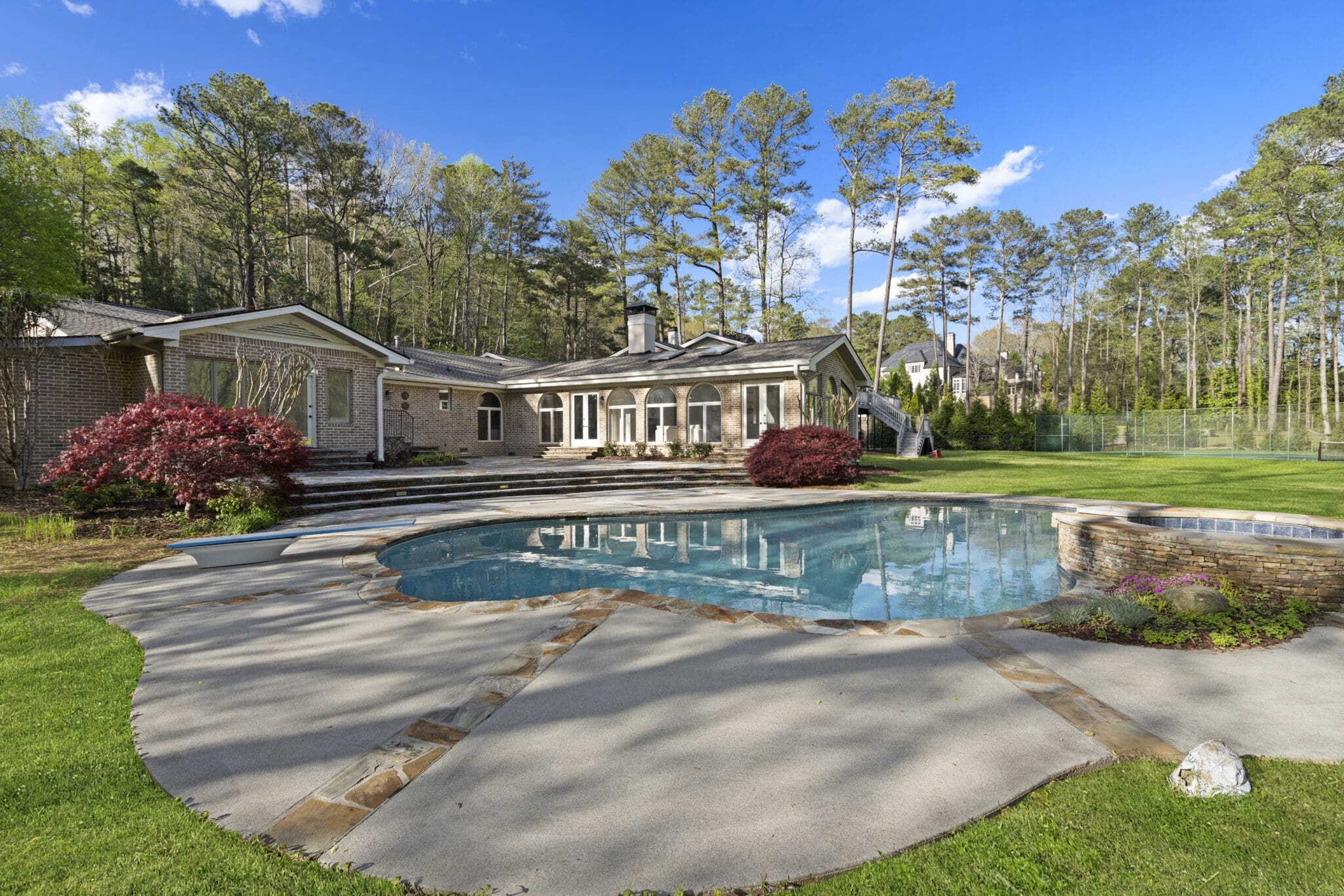 Swimming pool and brick house in a yard.